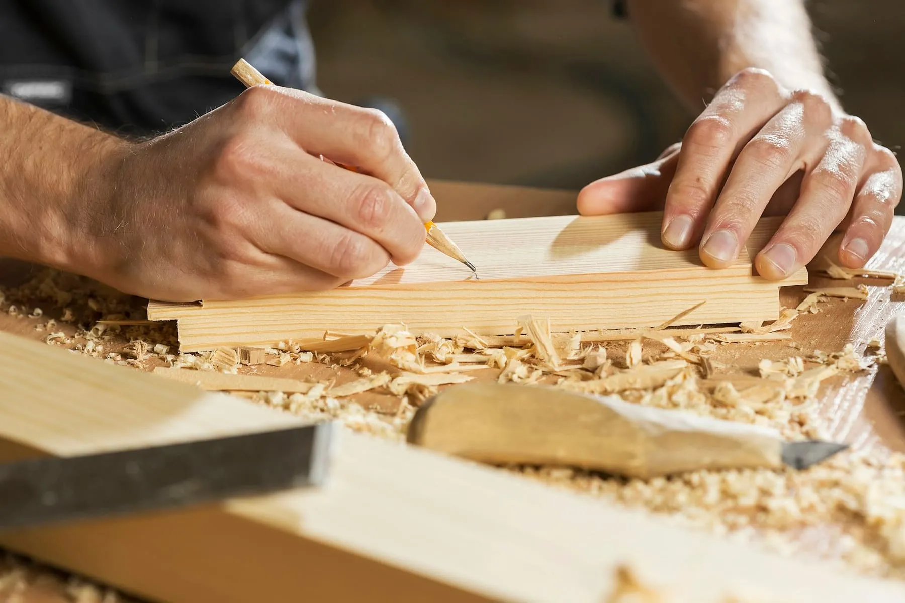 Charpentier traçant une pièce de bois au crayon dans l’atelier