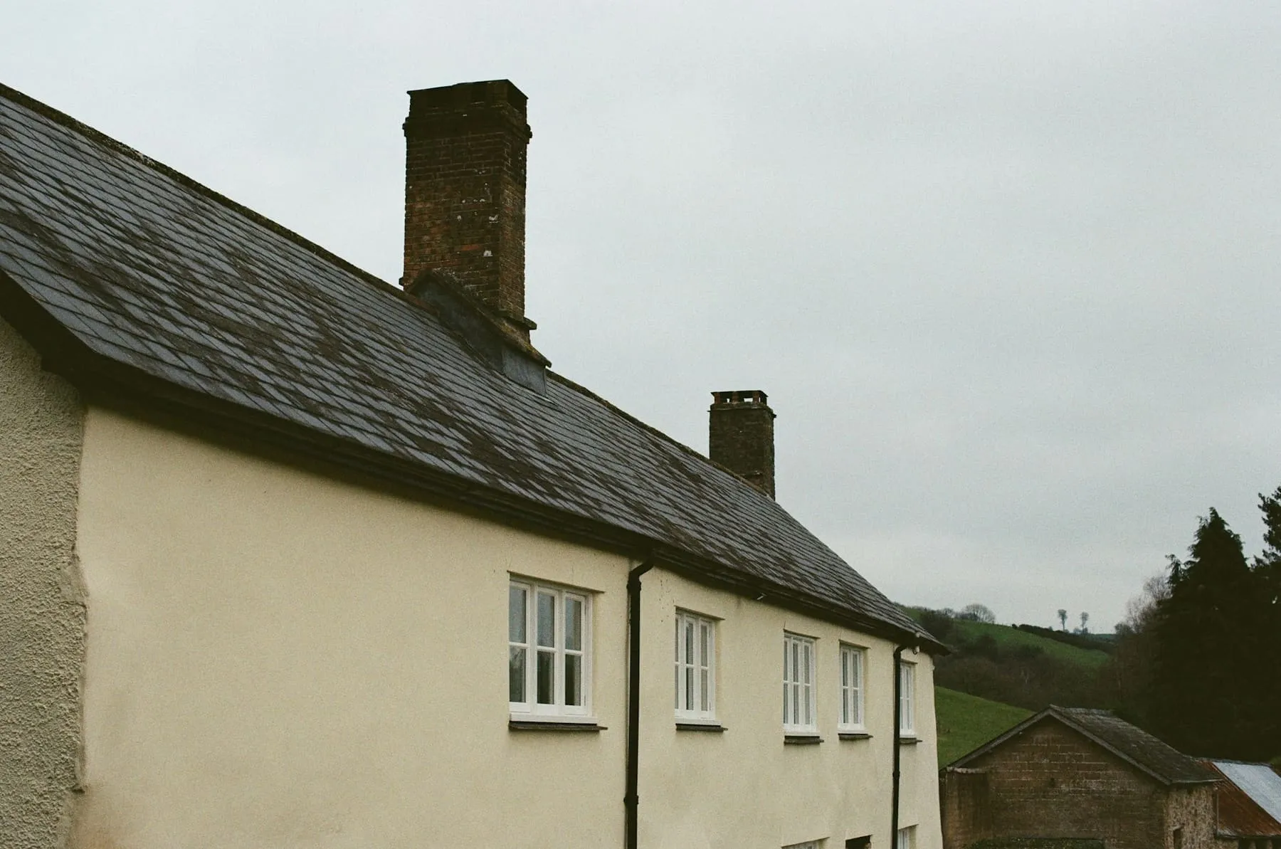Maison aux murs crème et au toit d’ardoise avec cheminées